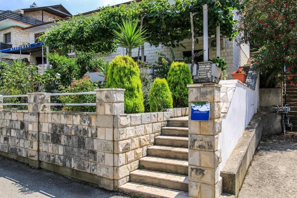 a stone retaining wall with stairs in front of a house at Apartments Ivana - free parking and 100m from the beach in Trpanj