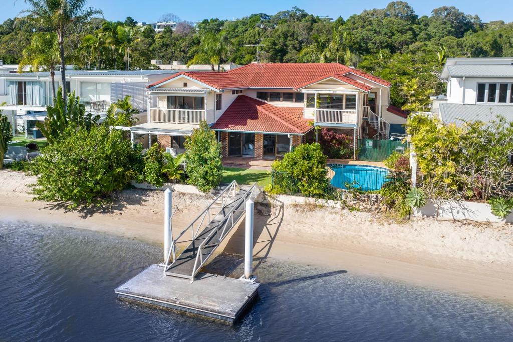 ein Haus am Strand mit einem Steg im Wasser in der Unterkunft Noosa Riverfront Splendour, Ideal for Families in Noosa Heads