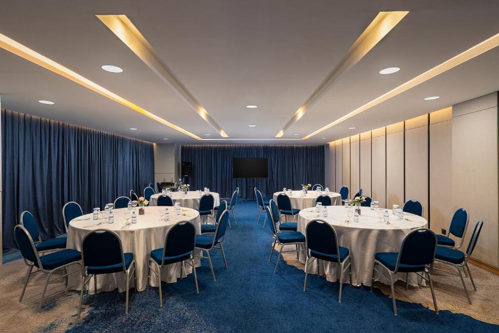a conference room with tables and chairs and a podium at Anara Airport Hotel in Tangerang