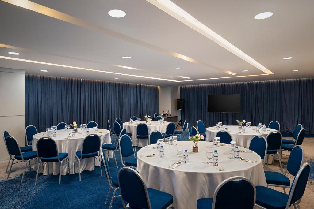 a conference room with tables and chairs and a screen at Anara Airport Hotel in Tangerang