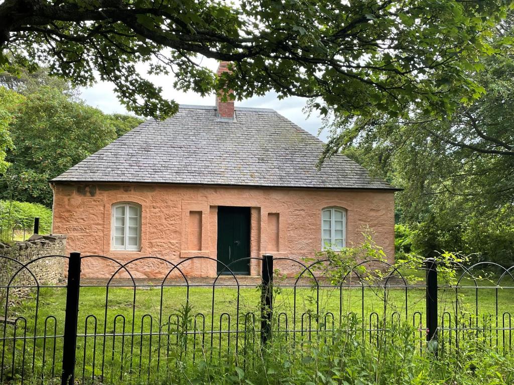 stary ceglany dom z płotem przed nim w obiekcie Ardlochan Lodge - Culzean Castle w mieście Maybole