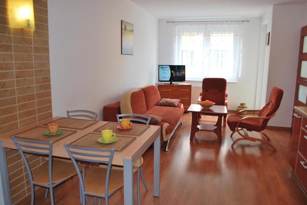 sala de estar con mesa, sillas y sofá en Apartamenty Zielone Tarasy, en Kołobrzeg