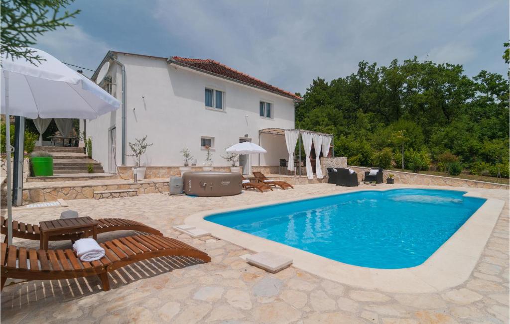 een zwembad met twee stoelen en een huis bij Cozy Home In Hrvace With Jacuzzi in Hrvace
