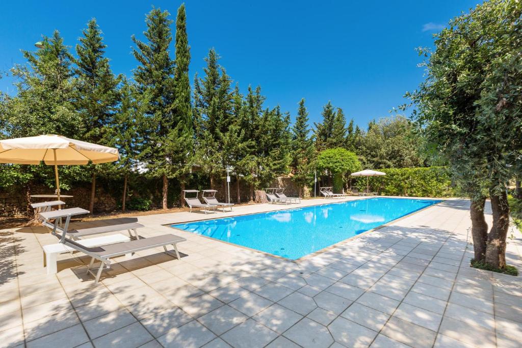 a swimming pool with two chairs and an umbrella at B&B Luxury da Salvatore in Presicce