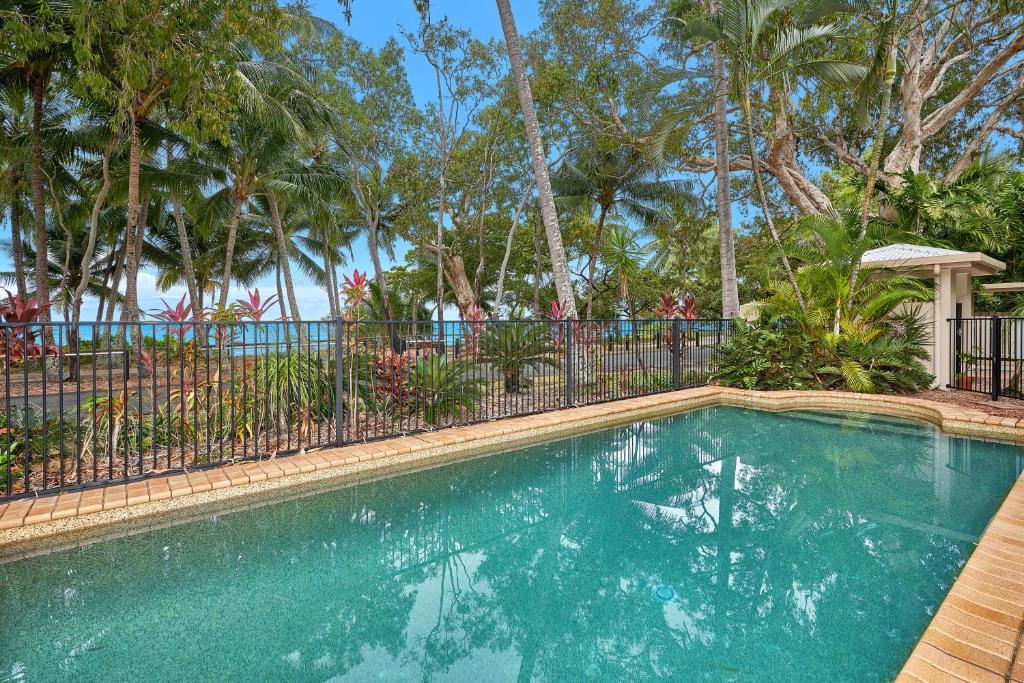 a swimming pool with a fence and palm trees at Coral Views at Clifton Beach in Clifton Beach