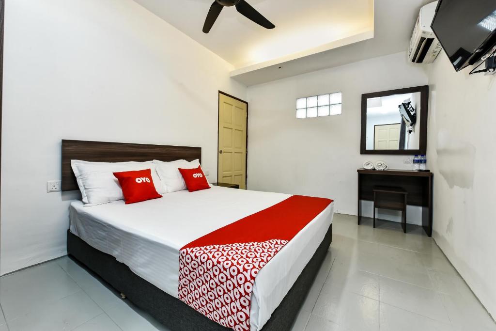 a bedroom with a bed with red pillows and a desk at Super OYO 90509 Usima Forest Resort in Ayer Keroh