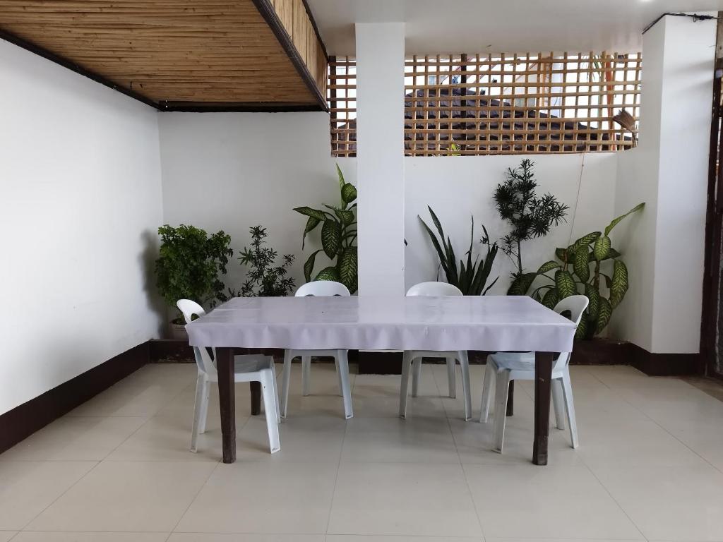 een witte tafel en stoelen in een kamer met planten bij Joyful Guest House in El Nido