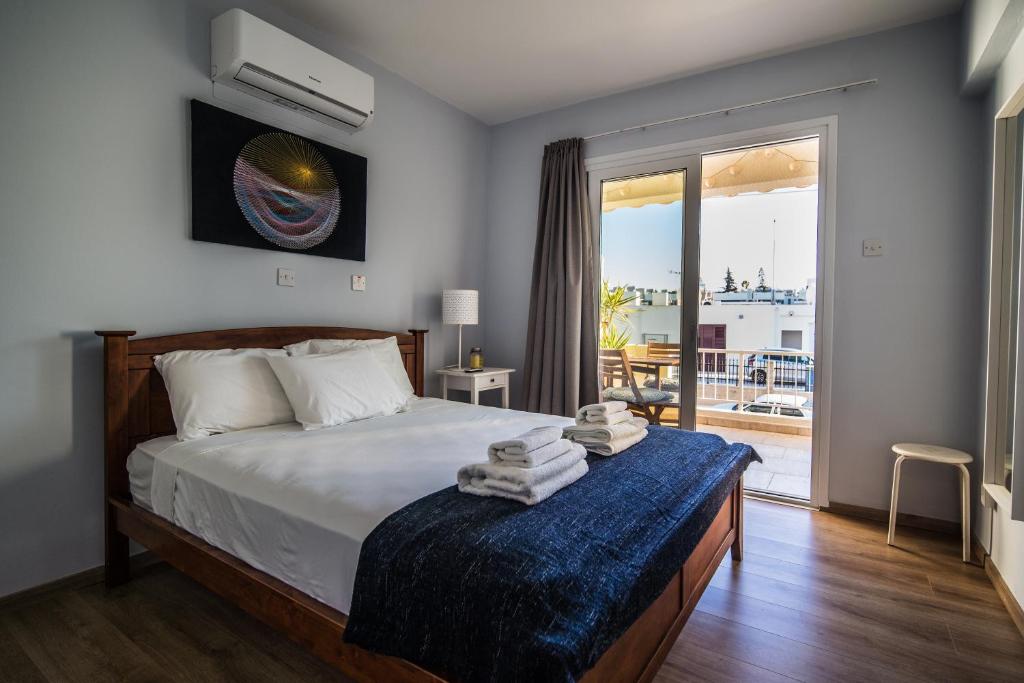 een slaapkamer met een bed en een groot raam bij Anemomylos guesthouse in Paralimni