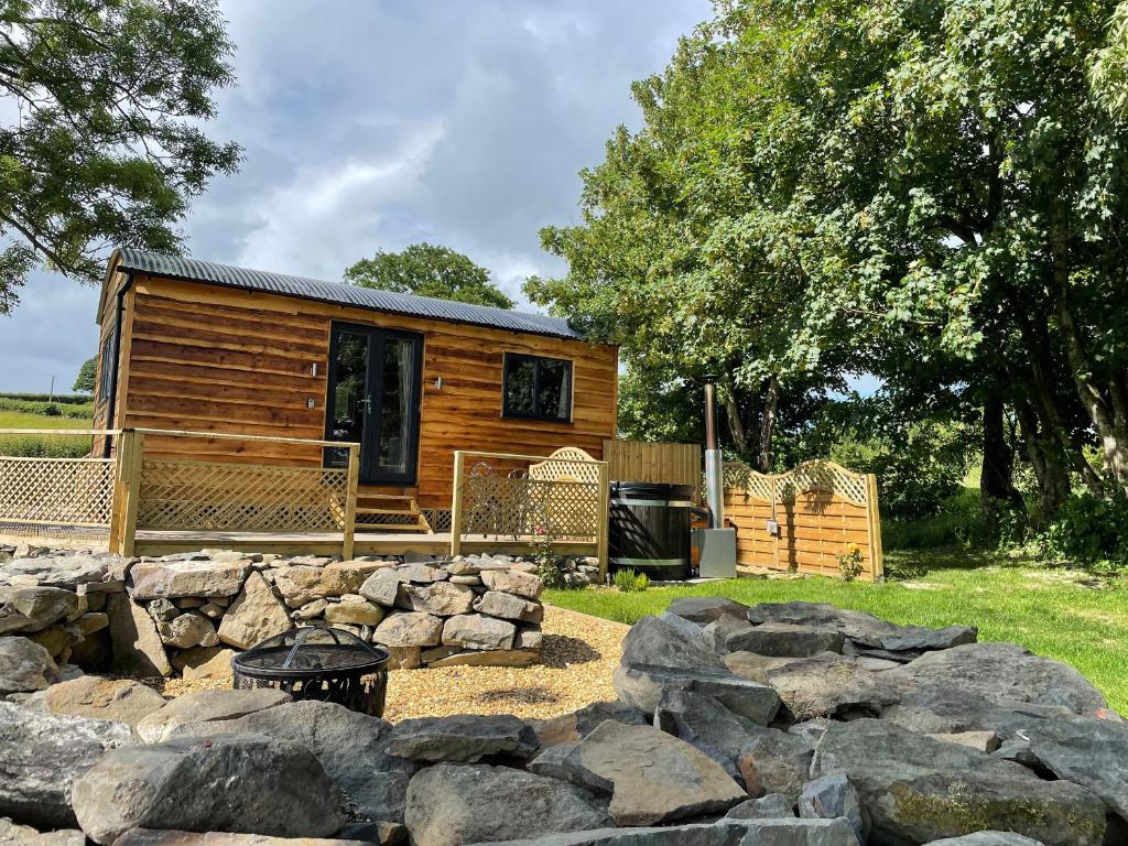 uma cabana de madeira com uma parede de pedra em frente. em Stag Lodge Pod em Welshpool