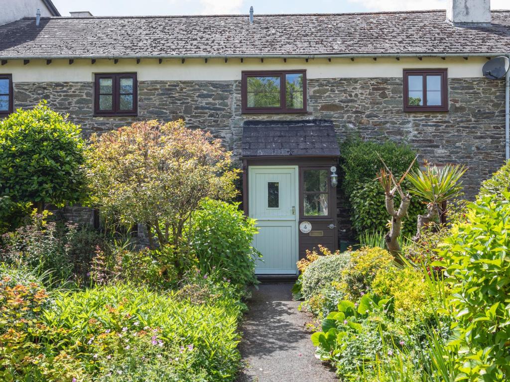 a stone house with a blue door and bushes at Oyster Cottage in Salcombe