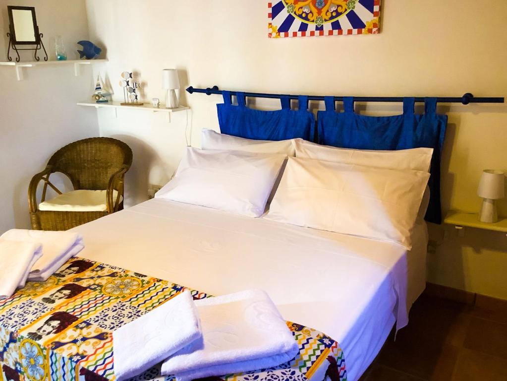 a bedroom with a large white bed with blue accents at Villamare in Custonaci