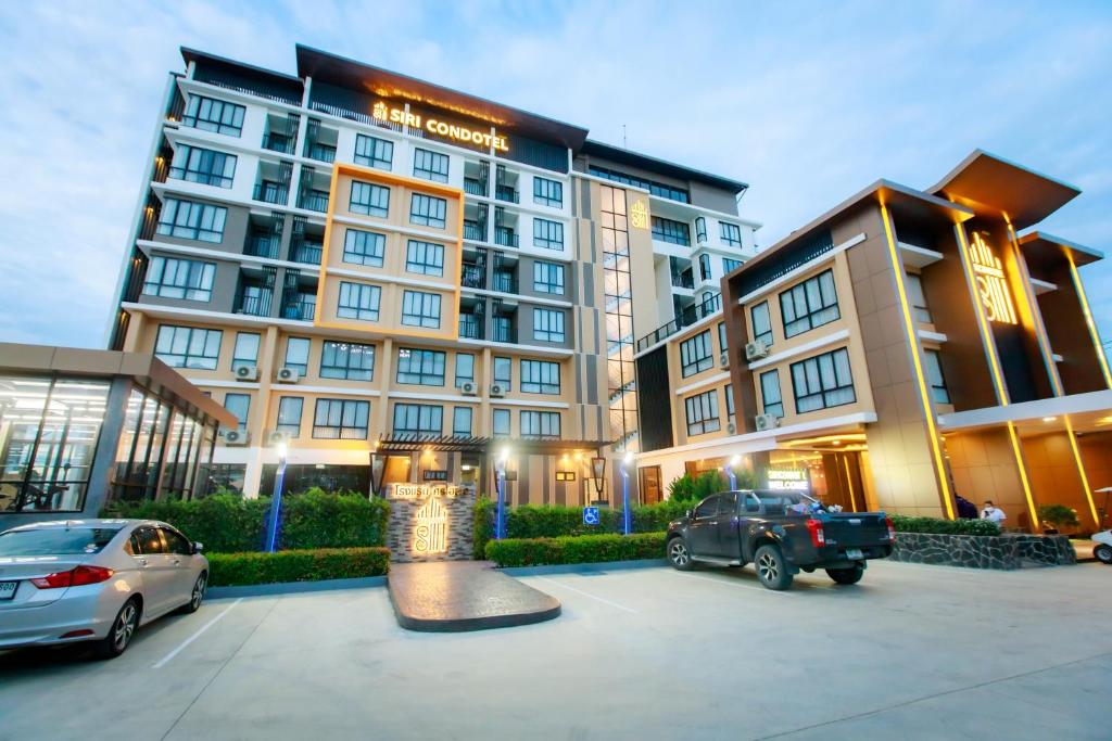 un gran edificio con coches estacionados en un estacionamiento en Siri Hotel Lumphun en Ban Pa Daet