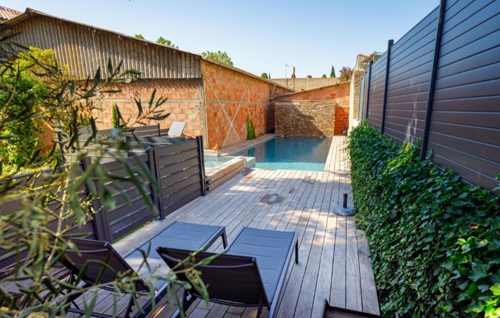 eine Terrasse mit 2 Stühlen und einem Pool in der Unterkunft La Bâtisse de jean in Béziers