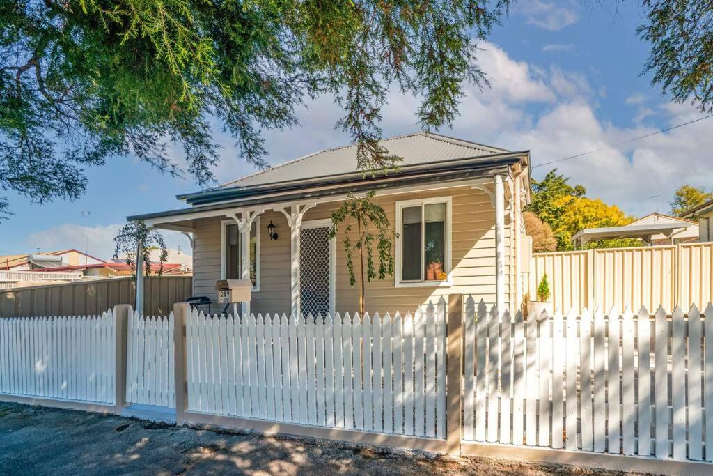 ein kleines Haus mit einem weißen Zaun in der Unterkunft Bright, Cosy Cottage near CBD- Free wifi, Netflix and Disney Plus in Orange