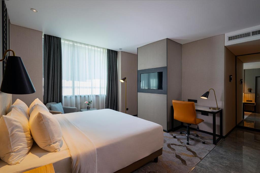 a hotel room with a large bed and a desk at Anara Airport Hotel in Tangerang