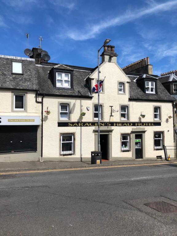 a large white building on the corner of a street at Saracen Head Hotel in Beith