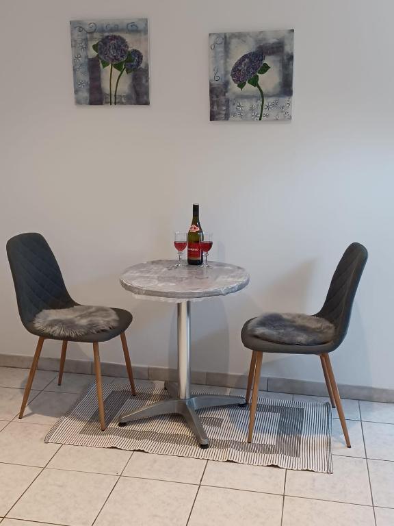 a glass table with two chairs and a bottle of wine at Maikammer in Wülfrath