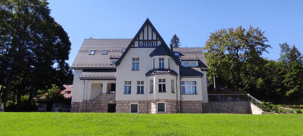 uma casa grande no topo de um campo verde em WILLA DobraNocka em Szklarska Poręba