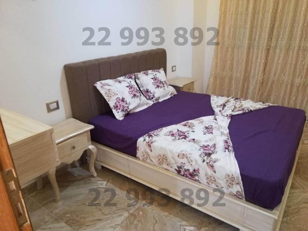 Un dormitorio con una cama con sábanas moradas y un escritorio. en S 2 1km from the beach in Kelibia en Qulaybīyah