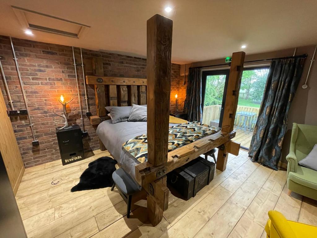 um quarto com uma cama de madeira e uma parede de tijolos em The Mash Tun - monstrous swank in a sleepy village em Whaplode
