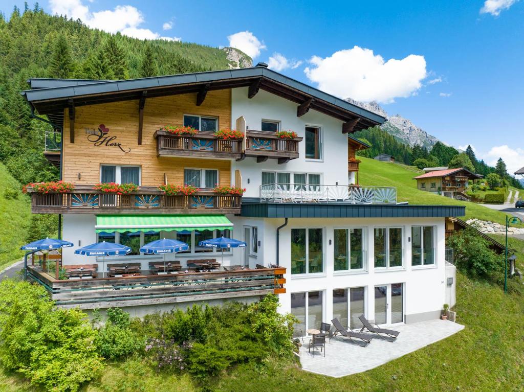 ein großes weißes Gebäude mit blauen Sonnenschirmen in der Unterkunft Hotel Tiroler Herz in Hinterhornbach