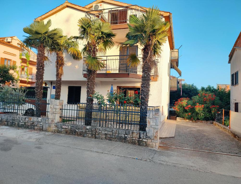 a house with palm trees in front of a fence at Apartments Novigrad in Novigrad Istria