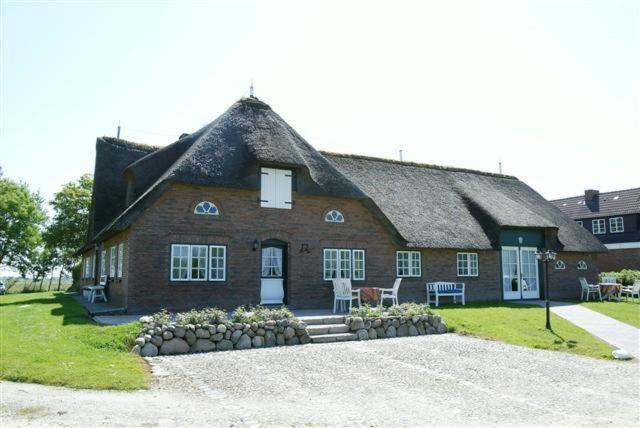 a large brick house with a thatched roof at Aarnhof-Wohnung-Schwalbe in Archsum