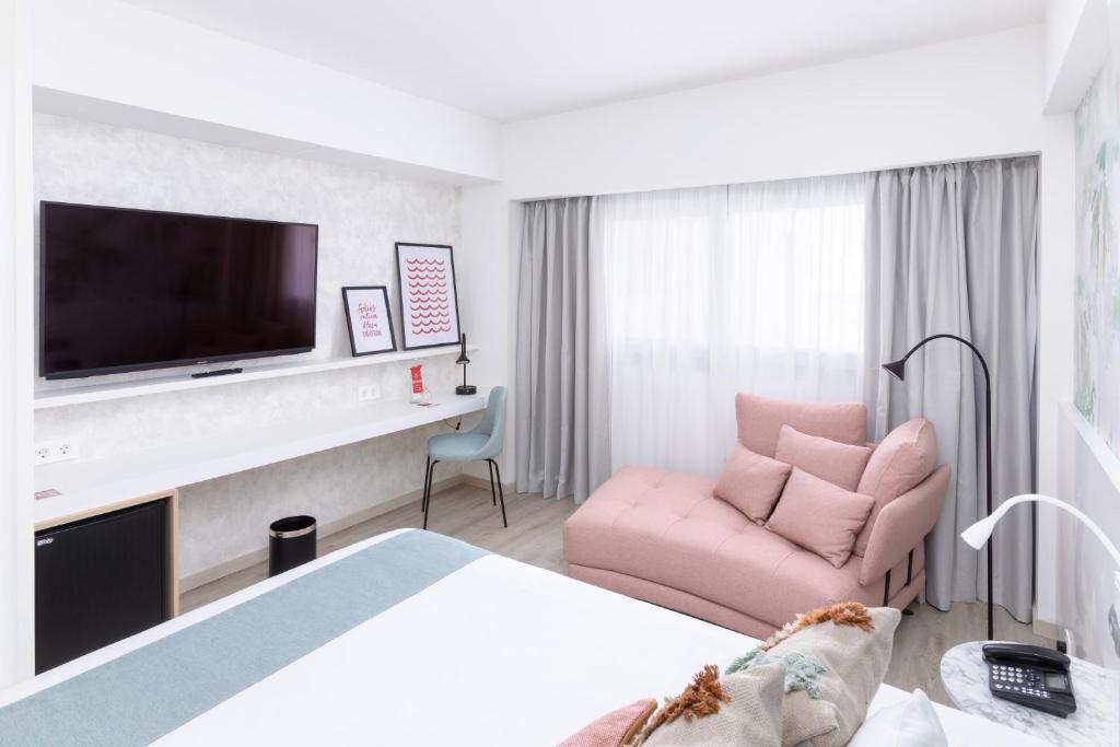 a hotel room with a pink chair and a television at Hotel Cristina by Tigotan Las Palmas - Adults Only in Las Palmas de Gran Canaria