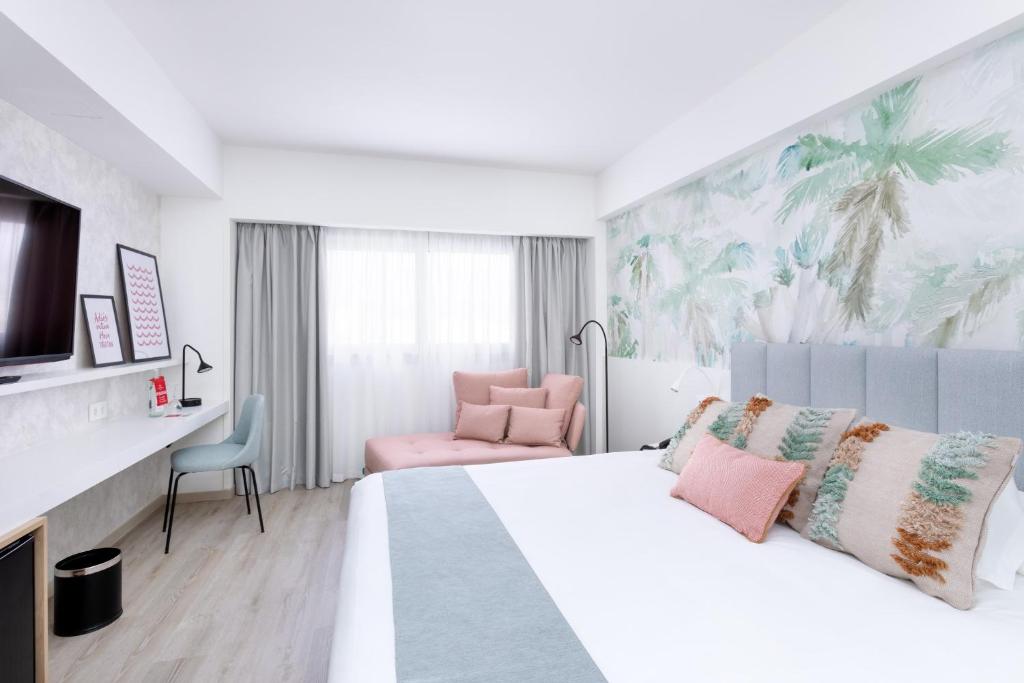 a hotel room with a bed and a chair at Hotel Cristina by Tigotan Las Palmas - Adults Only in Las Palmas de Gran Canaria