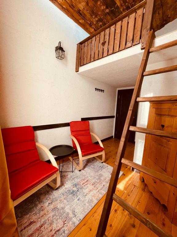 two red chairs and a table in a room at Cabana Vanatorului 8 in Râşnov