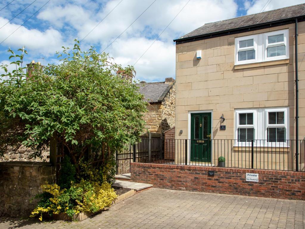 a brick house with a green door and a fence at 1 Wesley Mews in Alnwick