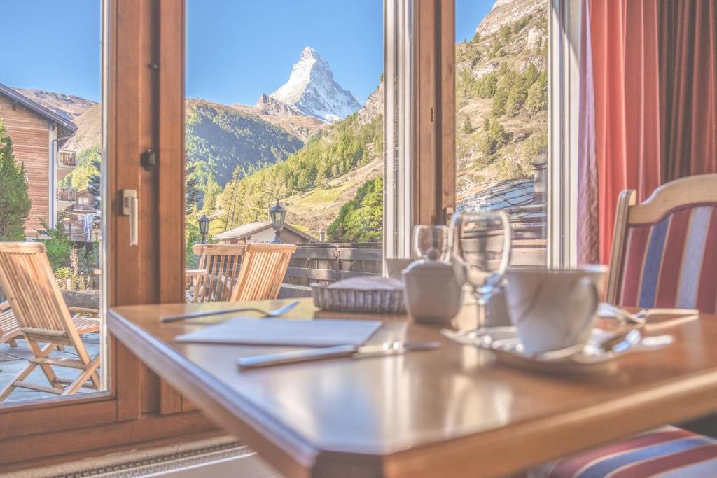 einen Tisch mit Bergblick durch ein Fenster in der Unterkunft Antares Hotel in Zermatt