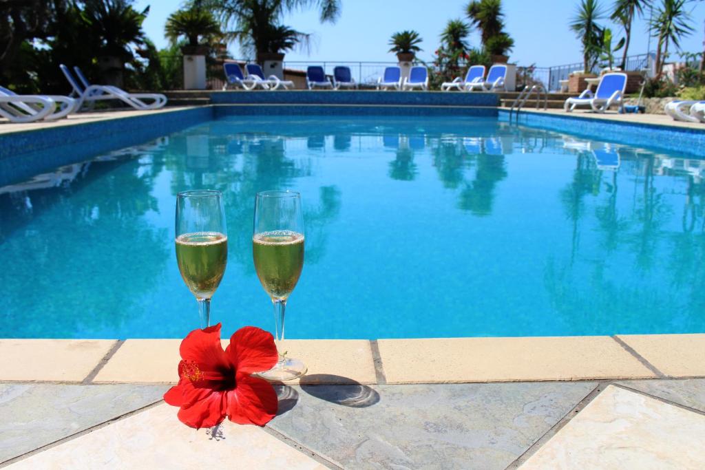 IoppoloにあるArenas Hotelのスイミングプールの横にシャンパン2杯と赤い花