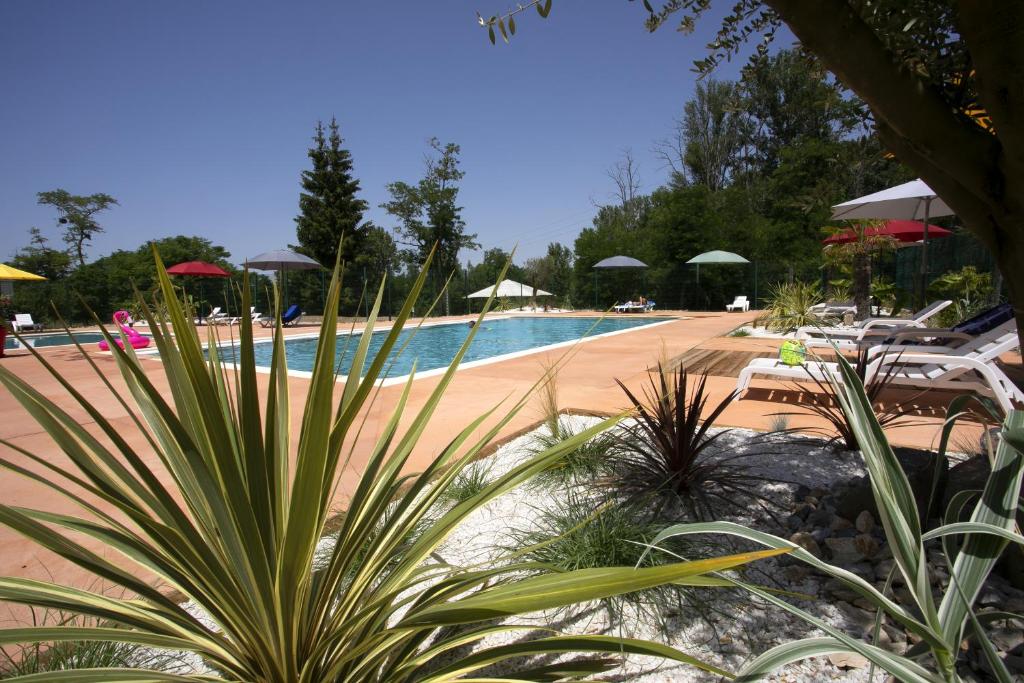 a swimming pool with chairs and umbrellas in a resort at La Bastide in Mazères