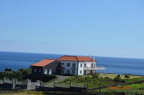 a white house with a red roof on top of a field at Vivenda da Saudade B&B in Angra do Heroísmo