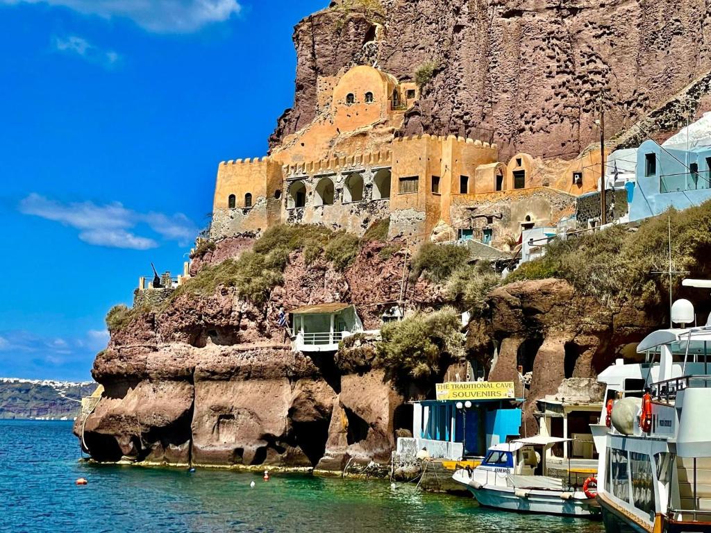 a building on the side of a mountain next to the water at Studio in Old Port of Fira Sea view Santorini in Fira