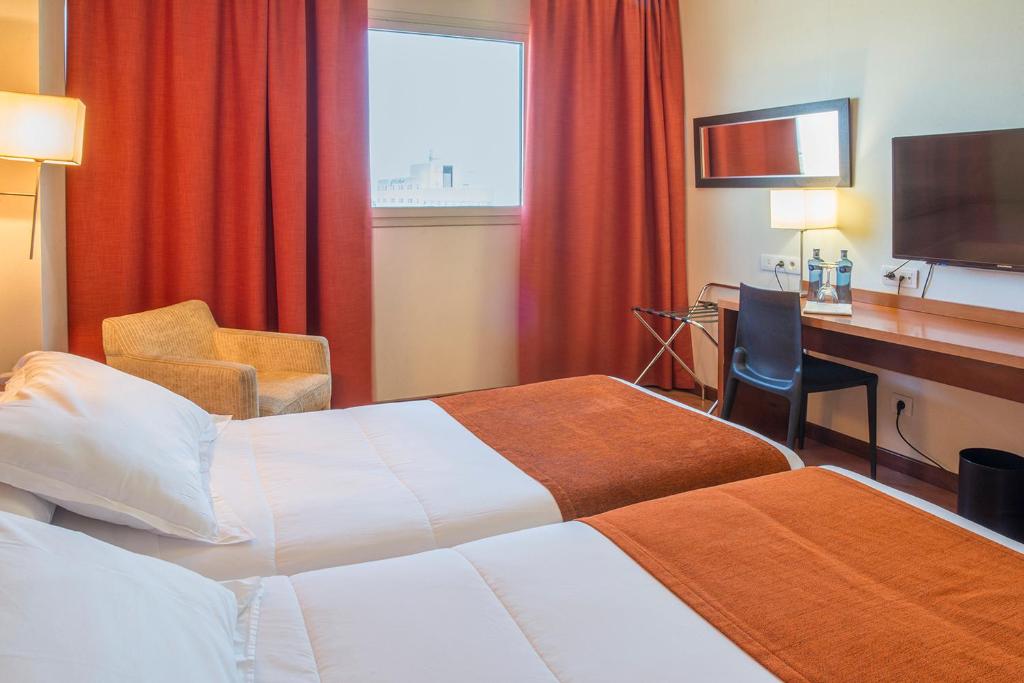 Habitación de hotel con 2 camas y escritorio en Hotel Xon's Valencia en Aldaya