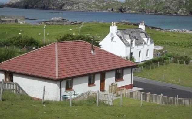 una casa bianca con un tetto rosso in un campo di Taigh an Uillt a Valtos