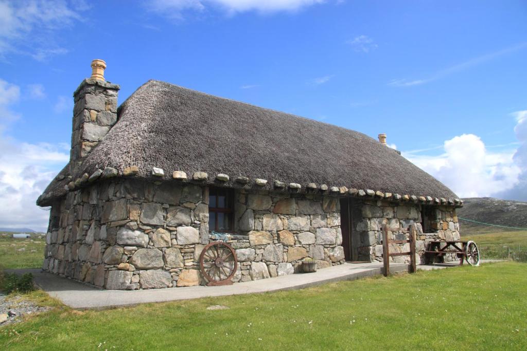 an old stone building with a grass roof at Smiddy Cottage in Pollachar