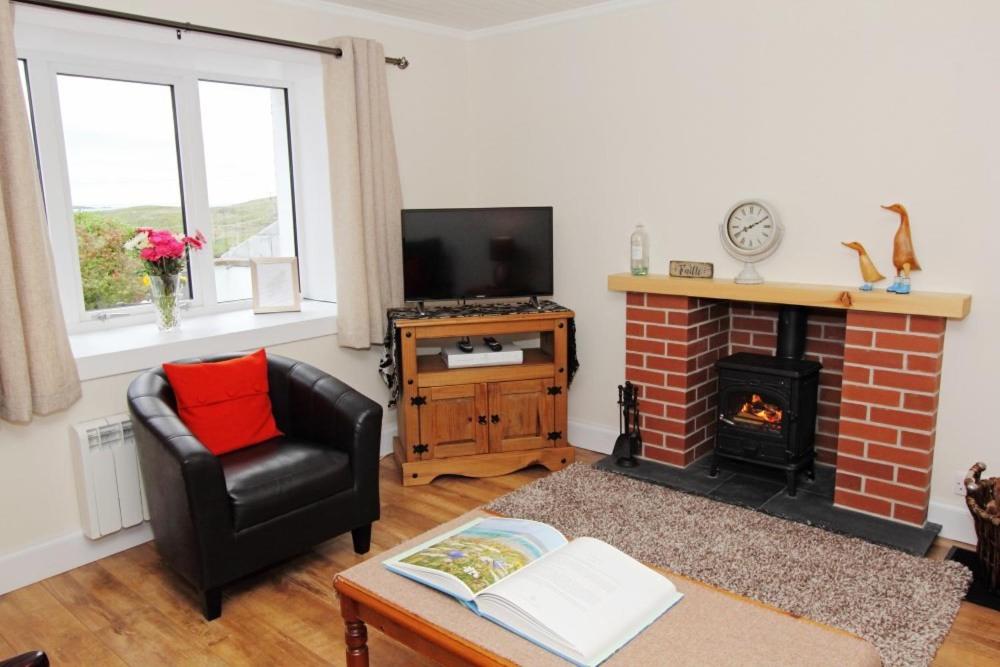 a living room with a fireplace and a chair at Old Post Office in Tarbert