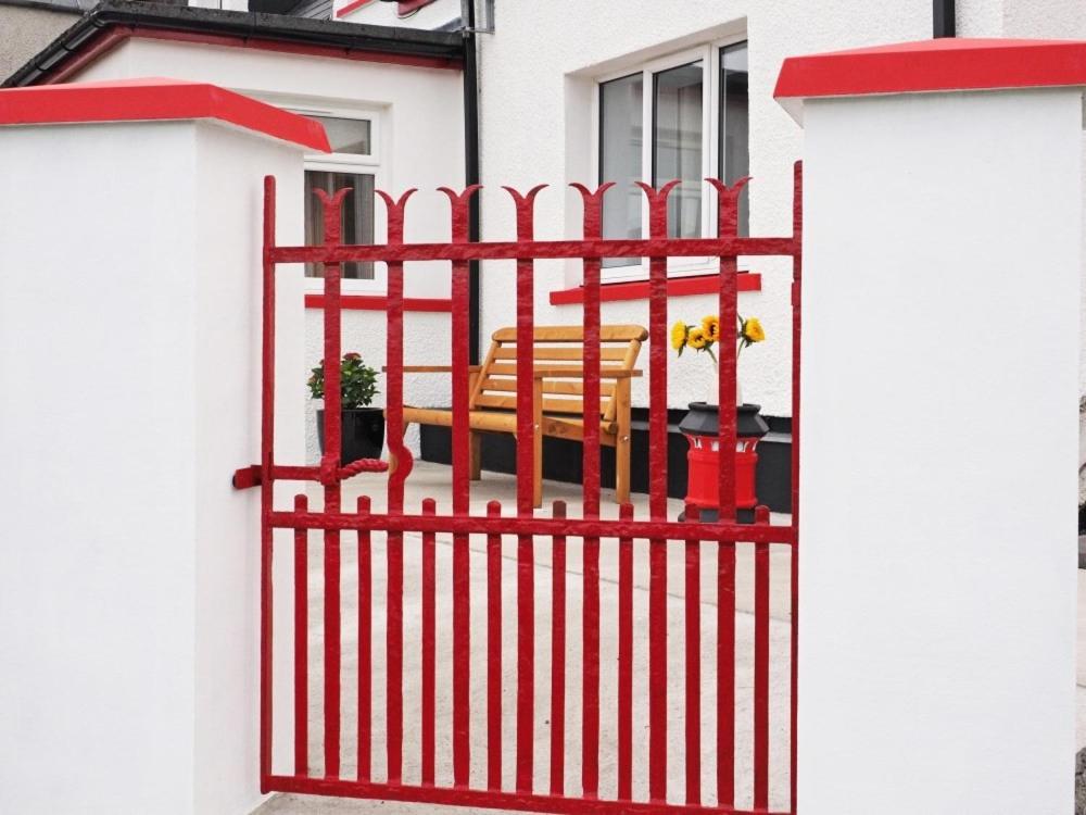 a red gate with two chairs on a house at Old Post Office in Tarbert