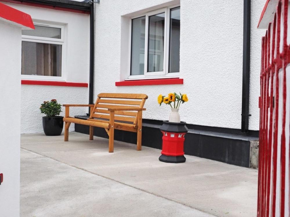 a bench and a vase of flowers on a sidewalk at Old Post Office in Tarbert