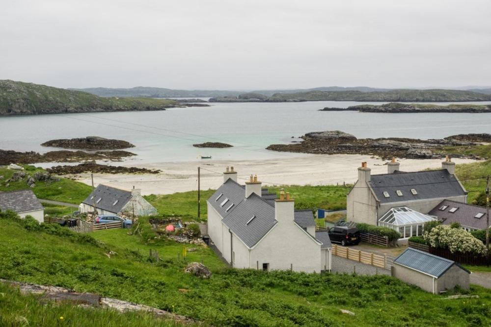 a group of houses on a hill next to a body of water at Taigh Eachainn in Valtos