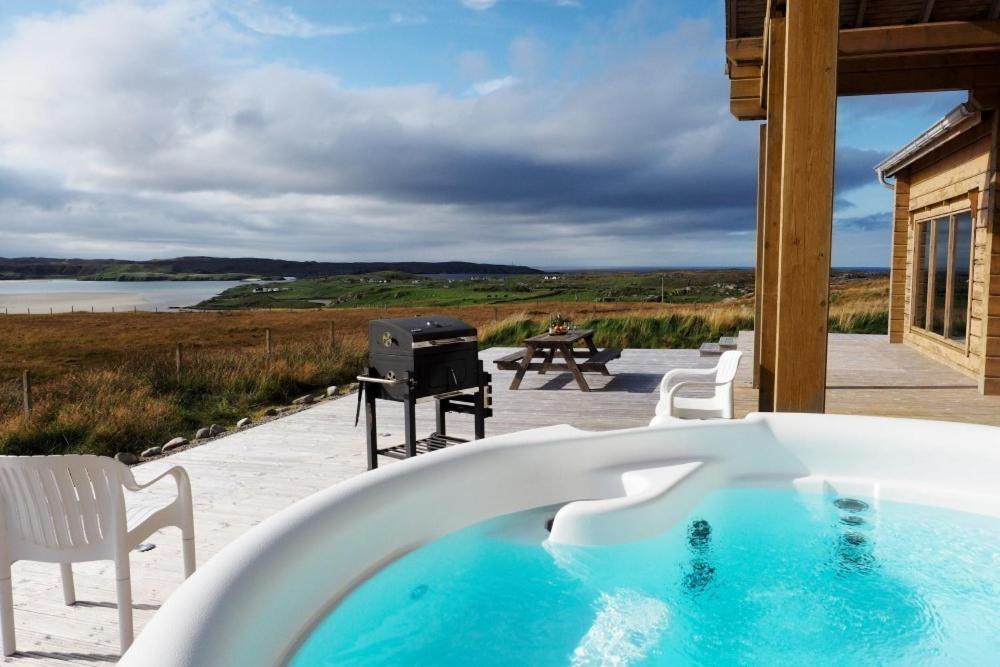 a hot tub on a patio with a grill at Eagle Lodge in Stornoway