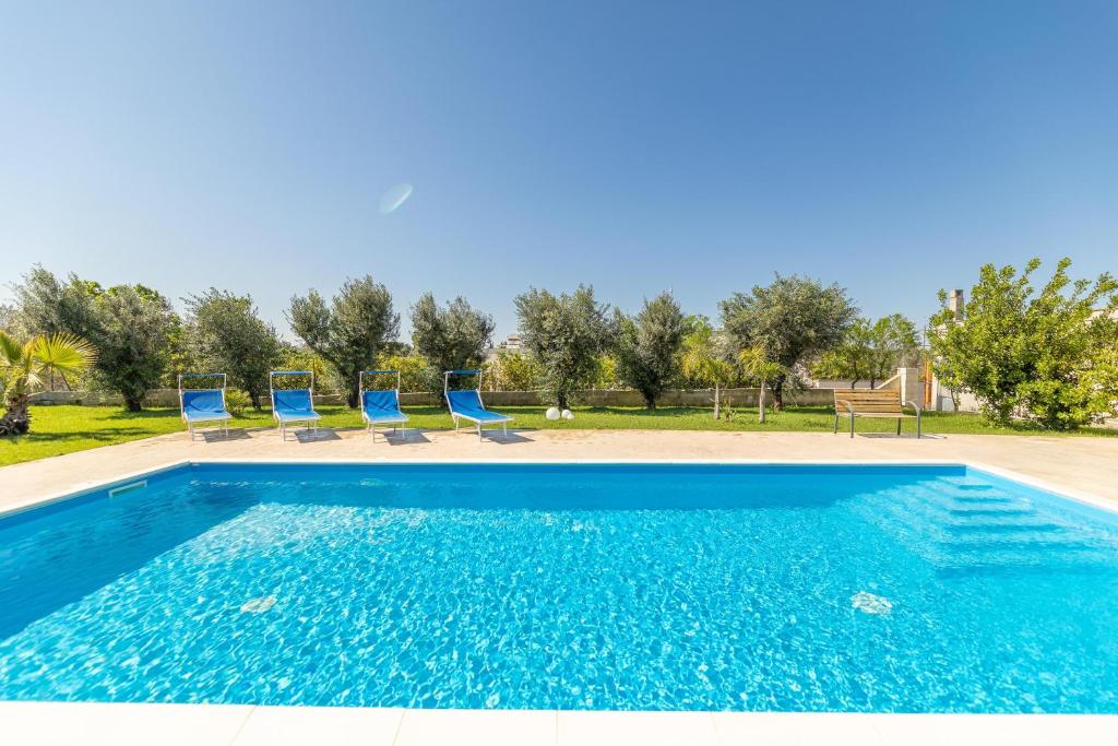 una piscina con sillas azules en un patio en Villa Campagnola, en Carpignano Salentino