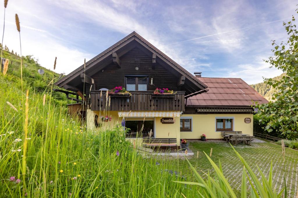 ein Haus mit einem Balkon mit Blumen darauf in der Unterkunft Almhütten Sonnblick & Almfried in Sonnenalpe Nassfeld
