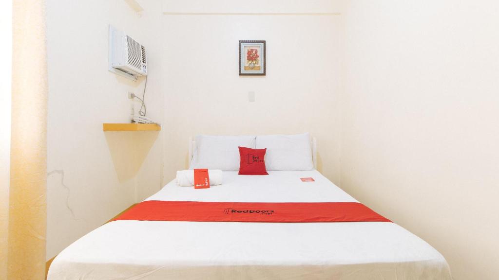 a bed in a room with a red pillow on it at RedDoorz @ Golden Skye Hotel Guagua in Guagua