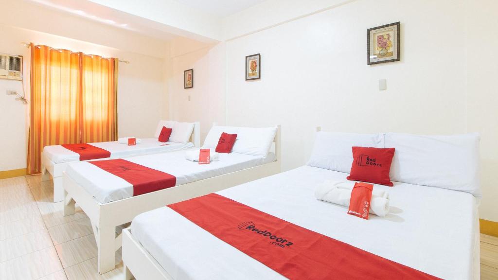 two beds in a hotel room with red and white sheets at RedDoorz @ Golden Skye Hotel Guagua in Guagua