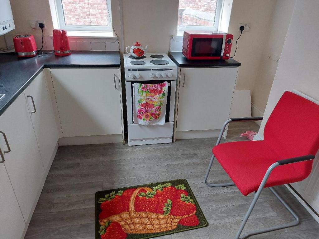 a small kitchen with a red chair and a microwave at The Cosy 2 bedroom flat, sleeps 6 in Hebburn-on-Tyne