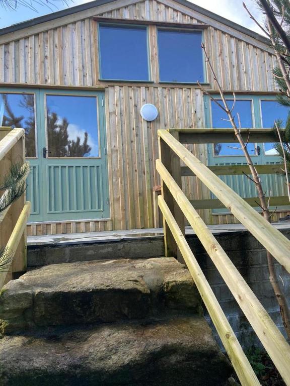 a wooden house with a door and a staircase with a frisbee at Rural Wood Cabin - less than 3 miles from St Ives in Penzance
